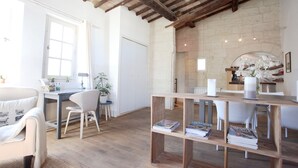 A spacious room with a wooden ceiling, a stone fireplace, and a dining area with a wooden table and chairs. - Magnificent Apartment in the heart of Uzès (Uzès)