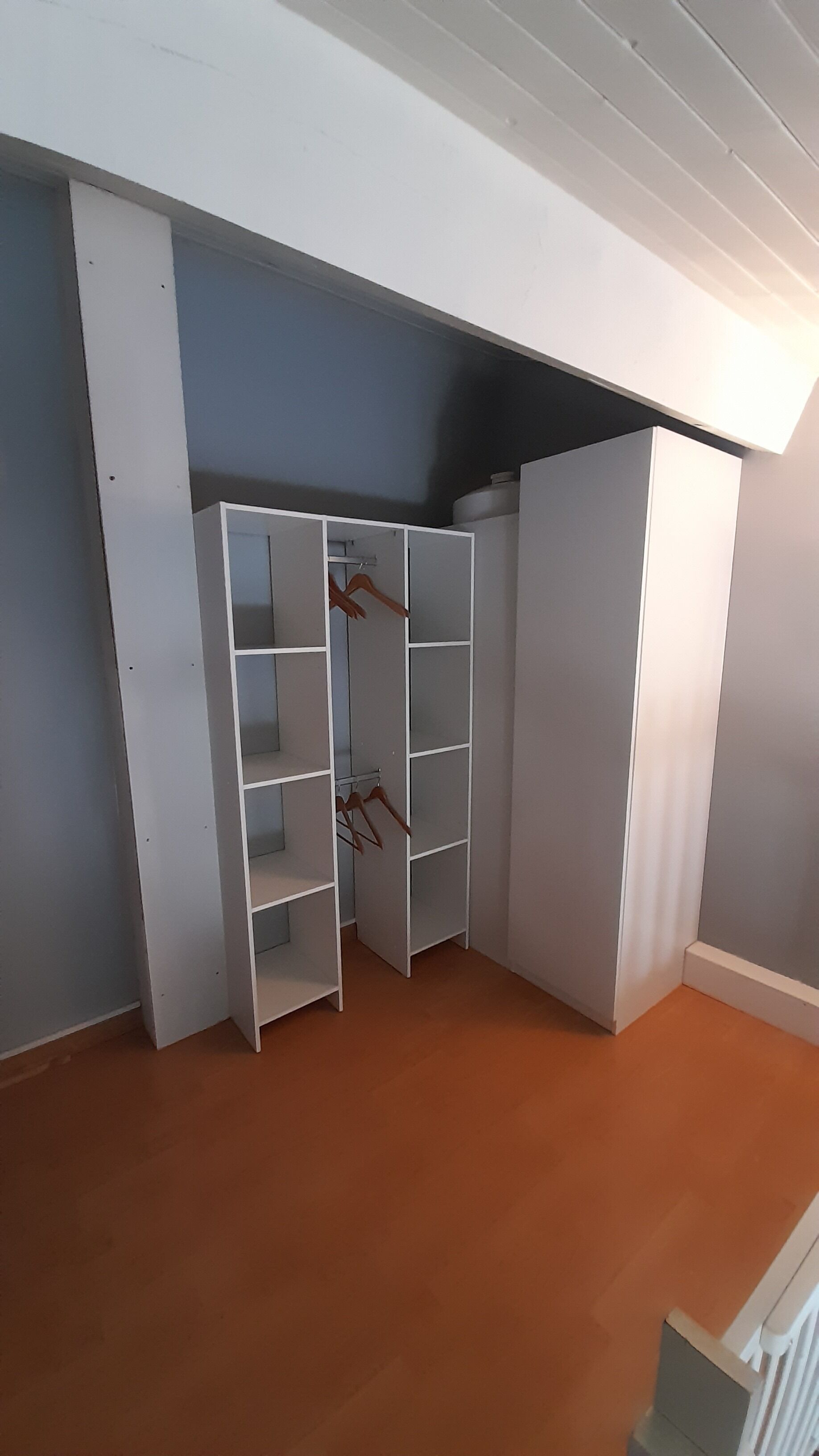 A corner room with a built-in closet featuring multiple shelves and hanging space.