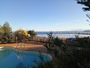 Una piscina con cubierta de madera y vista al océano.