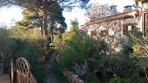 A garden pathway leading to a stone building with a tiled roof.