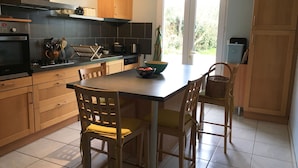 Een moderne keuken met houten kastjes, een centraal eiland en uitzicht naar buiten.