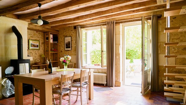 A rustic wooden interior with a dining table, chairs, a fireplace, and large windows. - L 'Abeille bleue - Cottage *** - 4/6 people - Azay-le-Rideau - from 70 € / night (Cheillé)