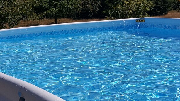 Una piscina azul clara con borde de azulejos y una escalera visible.
