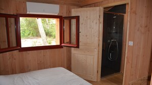 Una habitación de madera con una cama, ducha y ventana.