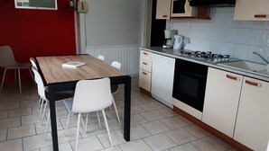 A compact kitchen with a wooden table, white chairs, a built-in oven, and a gas stove. - House 150m apartment in the city center, in a very quiet place (Gérardmer)