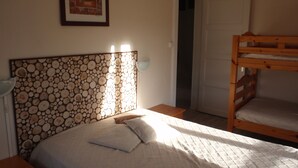 A bedroom with a bunk bed, a headboard with a circular pattern, a bedside table, a pillow, and a framed picture on the wall. - House 150m apartment in the city center, in a very quiet place (Gérardmer)