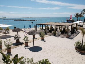 A beachside area with outdoor seating, umbrellas, and potted plants. - Exceptional Cote d'Azur, luxurious, 2 rooms, ground floor, direct beach access (Saint-Laurent-Du-Var)