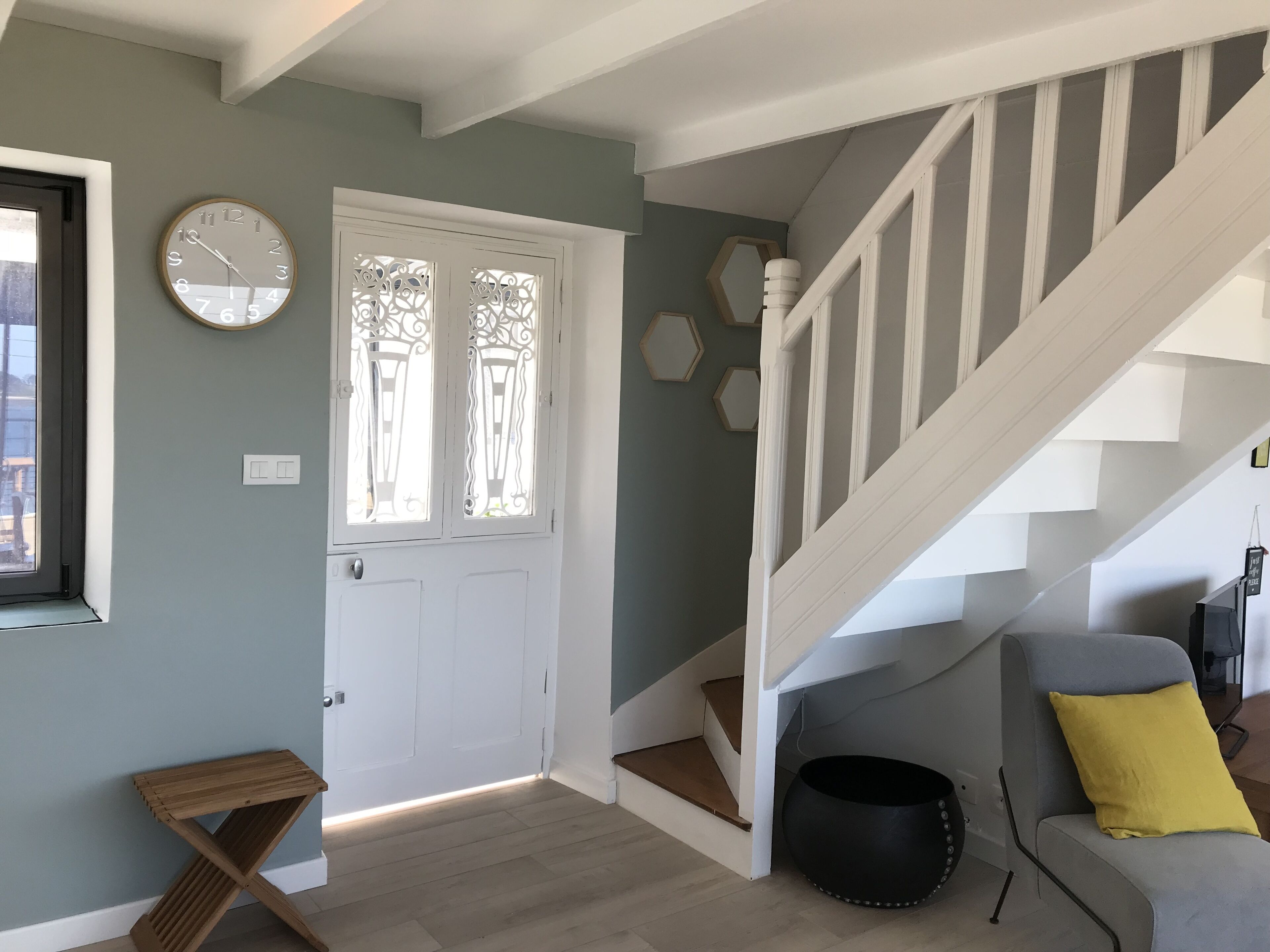 A staircase with white railings, a wooden door with decorative glass panels, and a round wall clock.