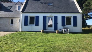 A two-story house with a sloped roof, white exterior, and blue shutters.