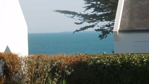 A coastal view with a clear sky, a body of water, and a building with a tiled roof.