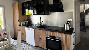A modern kitchen with wooden cabinetry, a dishwasher, an oven, and a coffee maker.