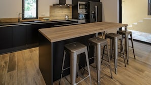 A modern kitchen with a wooden island, stainless steel appliances, and a large window. - 4-person villa with private pool, close to the sea  (Pianottoli-Caldarello)
