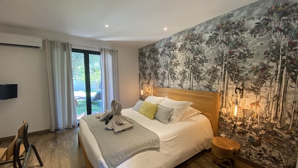 A modern bedroom with a large bed, a wooden headboard, a mural on the wall, and a view of the outdoors. - 4-person villa with private pool, close to the sea  (Pianottoli-Caldarello)