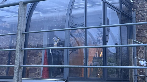 A conservatory with a stone roof and metal frame, attached to a brick building. - The enchanted barn  (Profondeville)