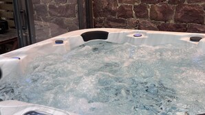 A hot tub with a control panel, set against a stone wall. - The enchanted barn  (Profondeville)