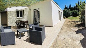 A modern outdoor patio with wicker furniture, a dining table, and a small kitchen area. - House surrounded by olive trees, set against a hill, on 2000 m2 of quiet land (Ceyreste)