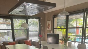 Eine moderne Küche mit Kochinsel, schwarzen Schränken und einem großen Fenster mit Jalousien.