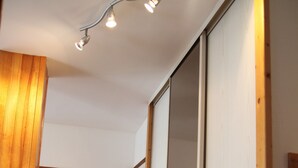 A hallway with wooden flooring, a wooden door, and a mirror on the wall.