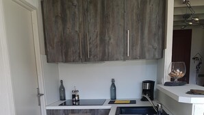 A compact kitchen with wooden cabinets, a sink, and a countertop. - A stay by the lake ... (Génos)