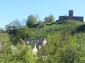 A hilltop building with a prominent tower, surrounded by lush greenery and trees. - A stay by the lake ... (Génos)