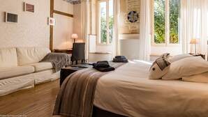 A hotel room with a bed, a sofa, a desk, and a window with curtains.