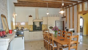 Una cocina con vigas de madera, una mesa de comedor con sillas, estufa y refrigerador.