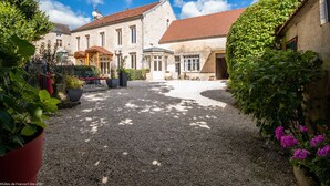 A courtyard with a gravel path, stone buildings, and potted plants.