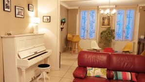 Un salón con un piano blanco, un sofá de cuero rojo y una mesa de centro de madera.