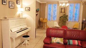 A living room with a white piano, a red leather sofa, and a wooden coffee table.