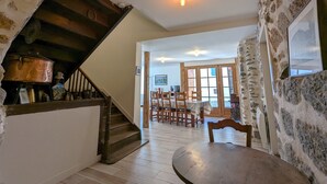 A rustic interior with a wooden staircase, a dining area with wooden chairs, and a stone wall. - Character cottage classified 3 stars Wifi Osse en Aspe - 9 people (Osse-en-Aspe)