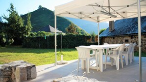 An outdoor patio with a stone table and chairs, a white umbrella, and a stone wall. - Character cottage classified 3 stars Wifi Osse en Aspe - 9 people (Osse-en-Aspe)