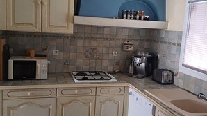 A kitchen with white cabinetry, a gas stove, a microwave, a toaster, and a coffee maker.