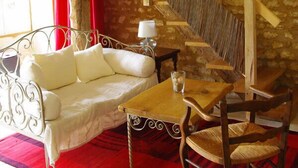 A rustic room with a wooden staircase, a white sofa, a wooden table, and a red carpet.