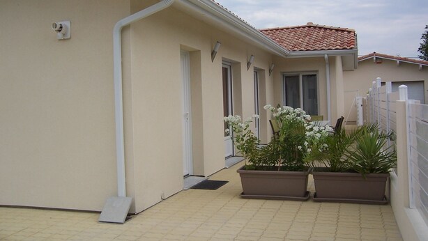 Un edificio con techo de tejas, fachada blanca y un patio con macetas y plantas.