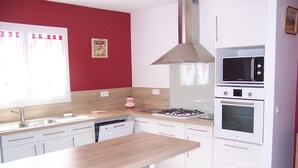 Una cocina moderna con armarios blancos, encimera de madera, estufa a gas, microondas y horno.