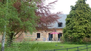 Ein Backsteinhaus mit grüner Rasenfläche, einem Holzzaun und einem großen Baum.
