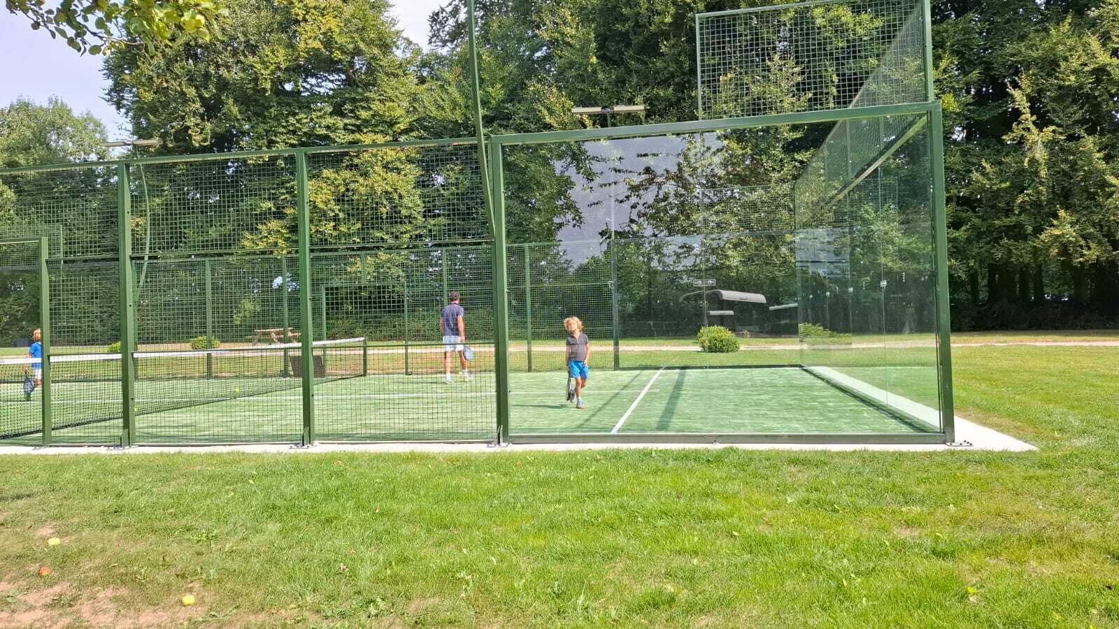 A tennis court with a net and a green fence.