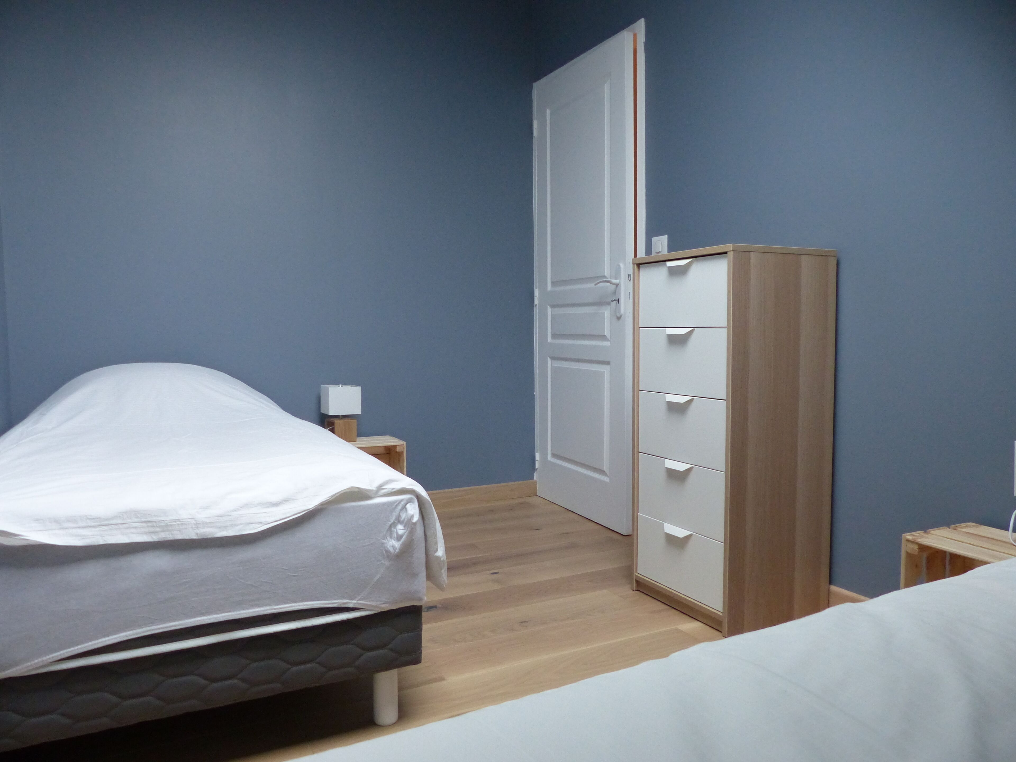 A bedroom with a bed, a wardrobe, and a nightstand.