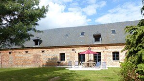 Ein Innenhof mit einem Backsteingebäude, einem Tisch mit Stühlen und einem roten Sonnenschirm.