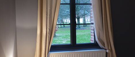 A room with a window, beige curtains, and a radiator.