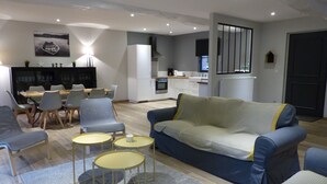 Ein modernes Wohnzimmer mit einer Couch, Sesseln, einem Couchtisch und einem Essbereich mit Tisch und Stühlen.