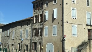 Un edificio de varios pisos con fachadas de piedra y yeso, numerosas ventanas y una entrada visible.