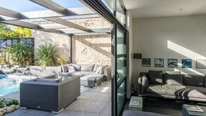 Uma área de estar moderna com piscina, assentos ao ar livre e uma parede de vidro.