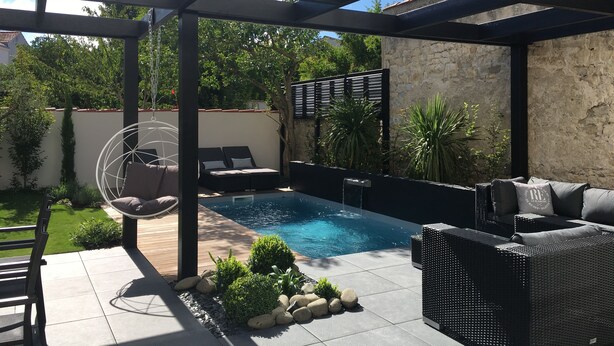 Espaço ao ar livre coberto com piscina, assentos e vegetação.
