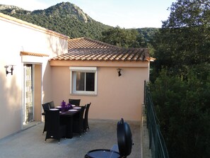 A patio with a table and chairs, a grill, and a view of a mountain. - LUXURY VILLA WITH ALL COMFORTS, SWIMMING POOL. (Porto-Vecchio)