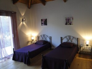 A room with two single beds, each with a headboard and a bedside table with a lamp. There are two wall-mounted lamps, a window with curtains, and a framed picture on the wall. - LUXURY VILLA WITH ALL COMFORTS, SWIMMING POOL. (Porto-Vecchio)