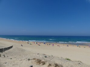 Una platja amb una tanca de fusta, sorra i un cel blau clar.