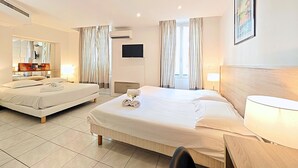 Una camera d'albergo con due letti, una televisione, una scrivania e una sedia.