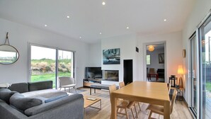 A modern living room with a sofa, TV, and dining area.