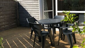 Una terraza de madera con una mesa, sillas, un ventanal de vidrio y un letrero con forma de estrella en la pared.